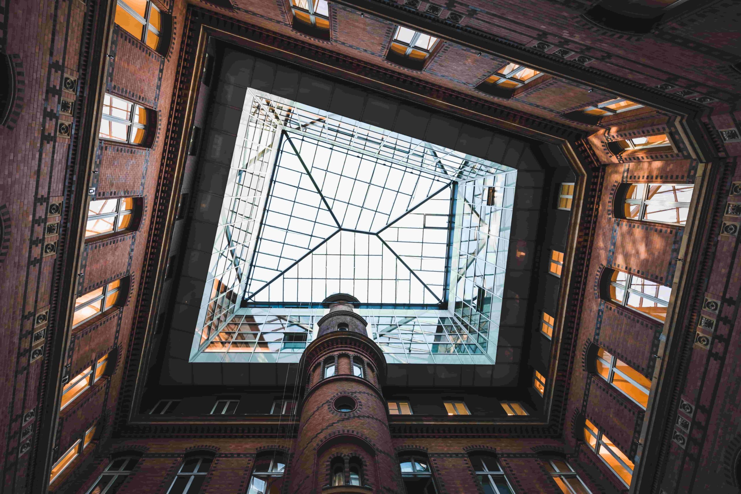 Architekturfotografie von unten: Historischer Backsteininnenhof mit modernem Glasdach – Beispiel für eine ungewöhnliche Perspektive